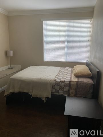 Corona apartment for rent - A bedroom with a bed, a nightstand, and a window with blinds.