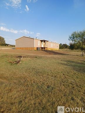 Kaufman house for rent - A large building with a grey roof is situated in a field.