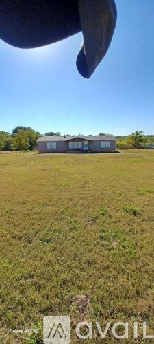 Kaufman house for rent - A house is situated in a field with a clear blue sky above.