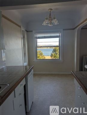 St. Helens apartment for rent - A room with two windows showing a view of a body of water and some trees.
