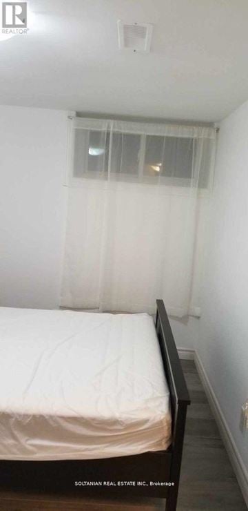 Toronto (West Hill) house for rent - A bedroom with a bed and a window with curtains.