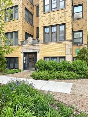 Oak Park apartment for rent - A building with a black door and windows with bushes in front.