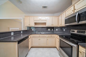 Columbus house for rent - A kitchen with wooden cabinets and black countertops.