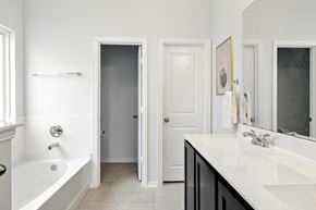 Houston house for rent - A white bathroom with a tub, sink, and mirror.