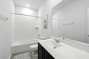 Houston house for rent - A white bathroom with a toilet, sink, and mirror.