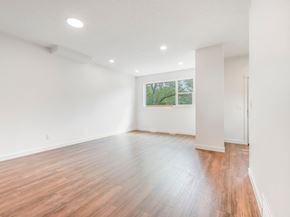 Edmonton apartment for rent - A room with wooden flooring and a window showing trees outside.