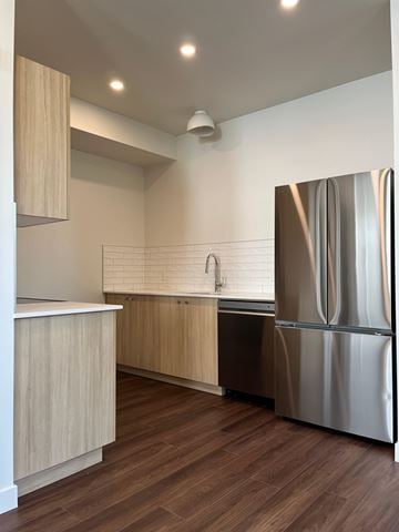 Edmonton apartment for rent - A modern kitchen with a stainless steel refrigerator and wooden cabinets.