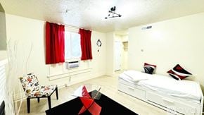 South Salt Lake apartment for rent - A bedroom with a bed, chair, and window with red curtains.