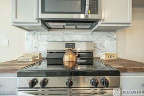 San Tan Valley house for rent - A modern kitchen with a stove top oven and a microwave above it.
