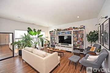 South Lebanon house for rent - A living room with a white couch, a grey armchair, a wooden coffee table, a bookshelf filled with books, and a large window.