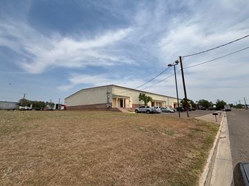 Laredo apartment for rent - A large building with a grey roof is situated in a grassy area with a road in front of it.