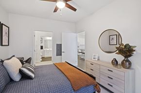 Fridley apartment for rent - A bedroom with a bed, dresser, mirror, and ceiling fan.