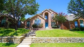 Rockwall house for rent - A house with a blue door and windows surrounded by a green lawn.