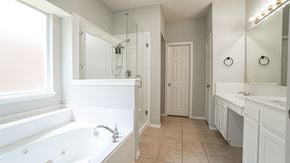 Rockwall house for rent - A white bathroom with a tub, sink, and mirror.