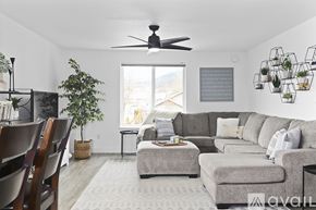 Grants Pass house for rent - A living room with a grey couch, a green plant, and a fan on the ceiling.