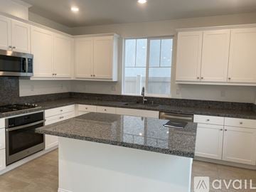 Redlands house for rent - A kitchen with white cabinets and a granite countertop.