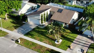 Delray Beach house for rent - A modern living room with a grey sofa and a black and white rug.