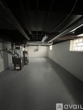 Cleveland Heights house for rent - A spacious, empty basement with concrete floors and walls, featuring a large window on the right side.