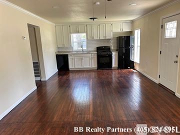 Tulsa house for rent - A kitchen with white cabinets and black appliances.