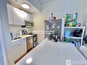 Boston apartment for rent - A kitchen with white cabinets and a refrigerator with magnets on it.