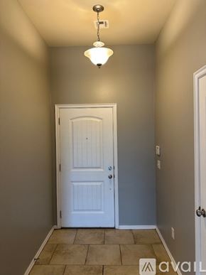 Oklahoma City house for rent - A grey door is at the end of a hallway with a brick wall on one side and a plant on the other.