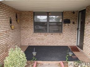 Oklahoma City house for rent - A small patio with a black mat and a small bush.