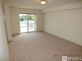 Seattle apartment for rent - A room with a carpeted floor and a sliding glass door leading to a parking lot.