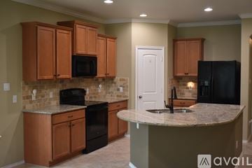 Leander house for rent - A kitchen with brown cabinets and black appliances.