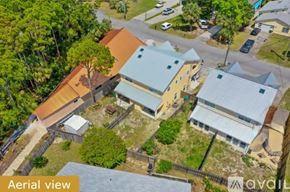 Panama City Beach townhouse for rent - A house with a blue roof is surrounded by trees and other houses.