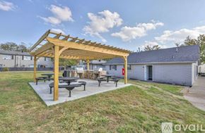 Nashville apartment for rent - A wooden pergola with benches is situated in a grassy area with a building in the background.