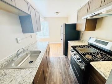 Washington Dc apartment for rent - A kitchen with a black refrigerator and a stove top oven.