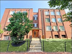 Washington Dc apartment for rent - A red brick building with a black fence and a tree in front.