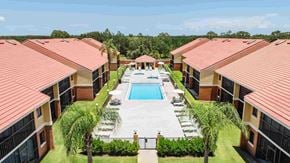 Kissimmee apartment for rent - A view of a pool surrounded by buildings and palm trees.