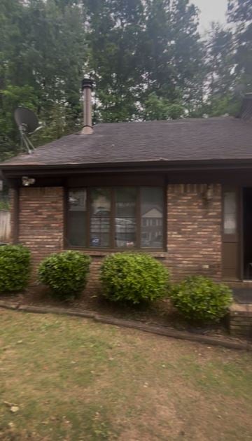 Birmingham house for rent - A house with a brown roof and a chimney is surrounded by green bushes.