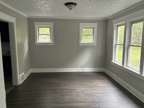 Akron house for rent - A room with wooden floors and three windows.