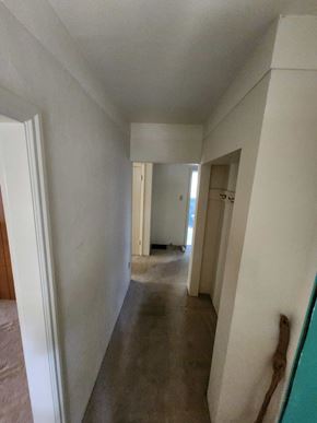 Victoria house for rent - A long white hallway with a door on the left and a door on the right.
