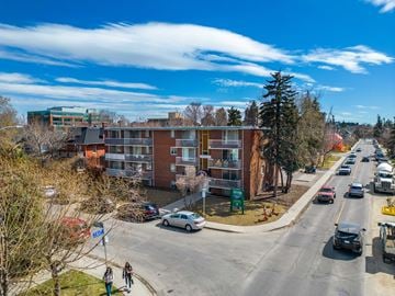 Calgary apartment for rent - A street view of a residential area with cars parked on the side of the road and people walking on the sidewalk.