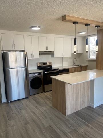 Calgary apartment for rent - A modern kitchen with a refrigerator, dishwasher, oven, and microwave.