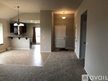 Edmond house for rent - A spacious living room with a grey carpet and a white door.