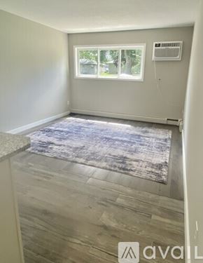Shakopee apartment for rent - A room with a rug on the floor and a window with a view of trees and a house.