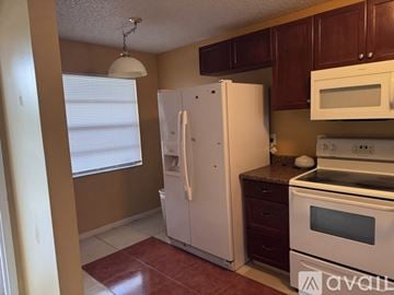Tamarac house for rent - A kitchen with brown cabinets and white appliances.
