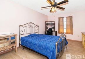 Palm Bay house for rent - A bedroom with a blue bedspread and a ceiling fan.