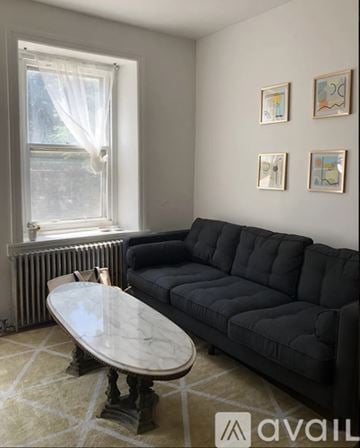 Philadelphia house for rent - A black couch sits in a living room with a round table in front of it.
