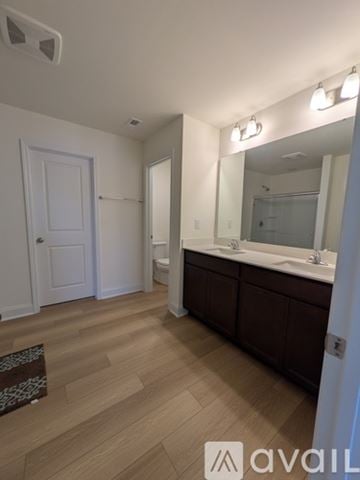 Angier house for rent - A bathroom with a white door, a mirror, and a wooden floor.