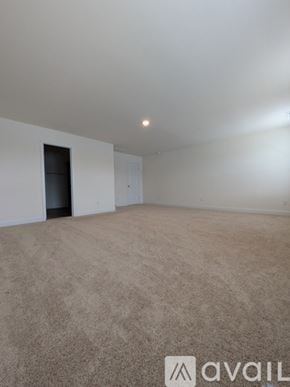 Angier house for rent - A room with beige carpet and white walls, with a door on the left and a light on the ceiling.