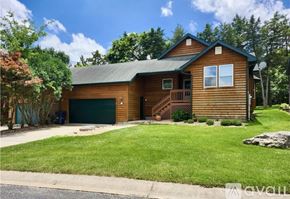 Camdenton house for rent - A wooden house with a green garage door and a stone pathway leading to the entrance.