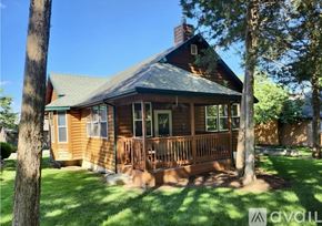 Camdenton house for rent - A house with a porch and a chimney is surrounded by trees.