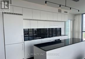 Toronto (Church-Yonge Corridor) condo for rent - A modern kitchen with white cabinets and black countertops.