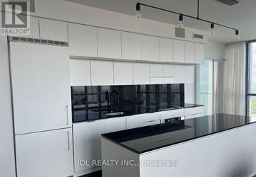 Toronto (Church-Yonge Corridor) condo for rent - A modern kitchen with white cabinets and black countertops.
