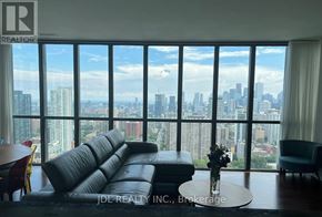 Toronto (Church-Yonge Corridor) condo for rent - A living room with a large window overlooking a city skyline.